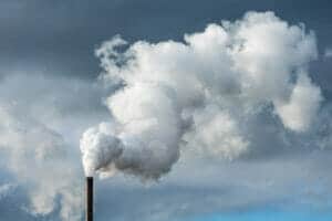 A smoke stack with billowing puffy steam